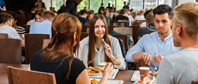 studierende essen in einer modernen mensa und unterhalten sich angeregt